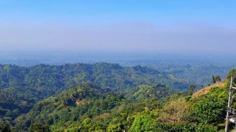 Rolling hills covered in lush green trees under blue sky Vídeo Stock 330467348