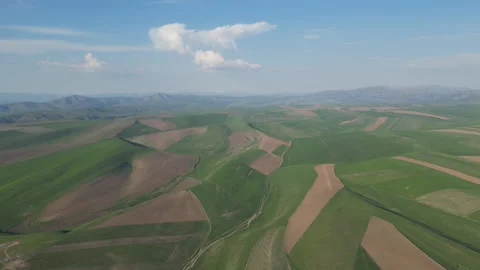 Rolling hills with a patchwork of green and brown fields under a bright sky. Video stock 334542733