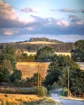 Rolling hills yellow fields and distant castle under cloudy sky in Burgundy.. Stock Photos