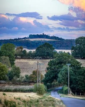 Rolling hills yellow fields and distant castle under cloudy sky in Burgundy.. Stock Photos