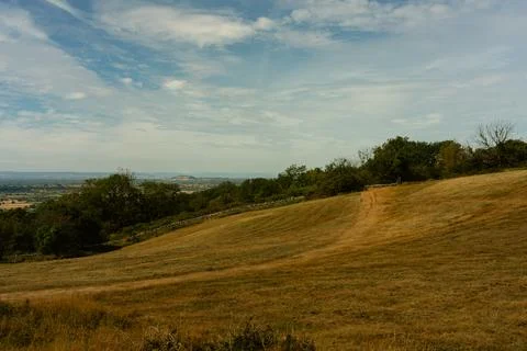 Rolling hillside and distant fields under a partly cloudy sky 스톡 사진