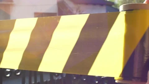 Rolling Out Black Yellow Caution Tape Stock Footage 131359398
