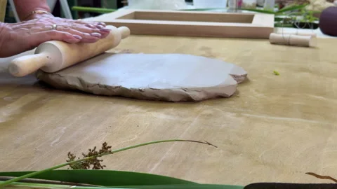 Rolling out clay sheet with a rolling pin to prepare base for plaster relief wit Видео 314186076