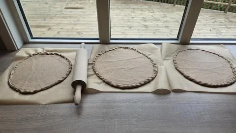 Rolling out dough for baking bread in a kitchen during the day Stock Photos