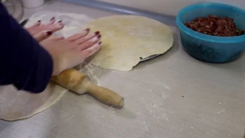 Rolling out the dough with a rolling pin on the kitchen table in a thin cake for Stock Footage 106888785