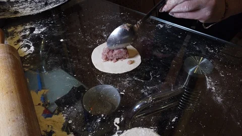 Rolling out the dough with a rolling pin on the kitchen table in a thin cake for Stock Footage 119278384