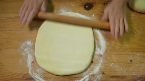 Rolling out dough with a rolling pin on a wooden board Stock-Footage 317038376