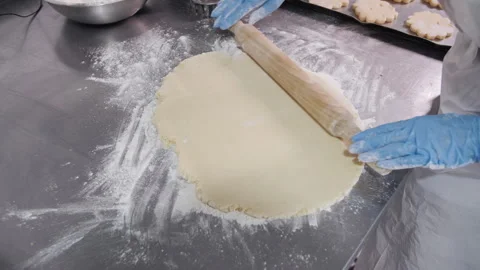 Rolling out the dough with a rolling pin manually. Bakery production. Stock Footage 321362984
