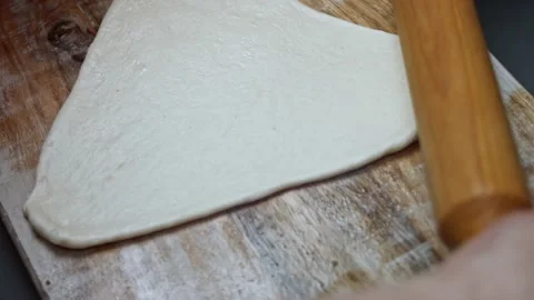 Rolling out fresh dough for pizza on wooden cutting board. Preparing heart Stock Footage 146654689