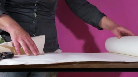 Rolling out lining wall paper on a table Stock Footage 158248365
