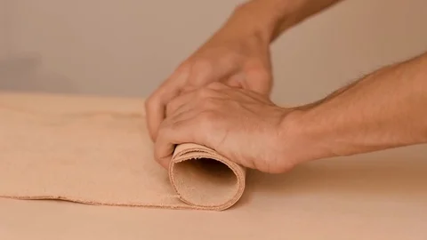 Rolling out a piece of raw vegetable tanned leather hide Stock Footage 126115576