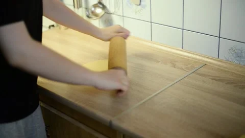 Rolling out raw pastry dough with a wooden rolling pin on a table Stock Footage 342704117