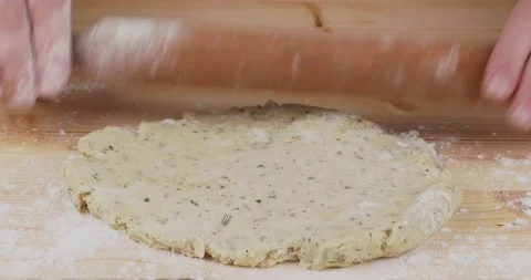 Rolling out a raw savoury dough on a wooden board with a rolling pin 스톡 동영상 133358675