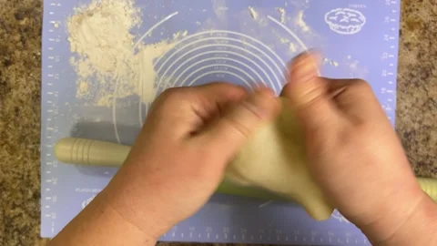 Rolling out round pieces of raw dough with a rolling pin to make patties.  Stock Footage 300456373