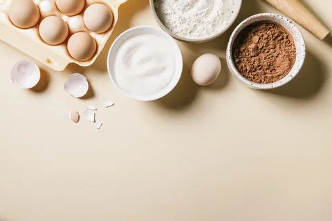 Rolling pin and baking ingredients. Flour, eggs, sugar, and cocoa powder. Stock Photos
