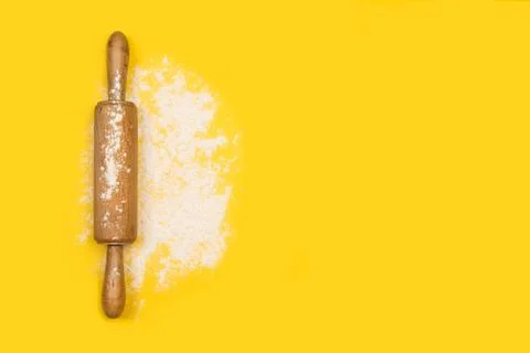 Rolling pin with flour on a yellow background in a top view Foto stock