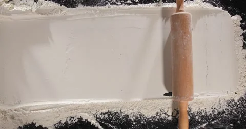 Rolling pin moving through flour across frame baking process Stock Footage 332235073
