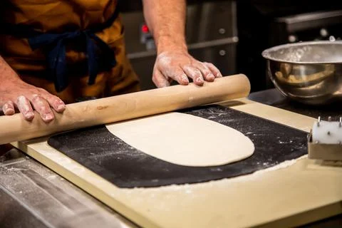 Rolling Pizza Dough on Table in Professional Gourmet Kitchen Stock Photos