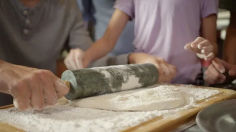 Rolling pizza dough while child sprinkles flour on top Stock Footage 123734137