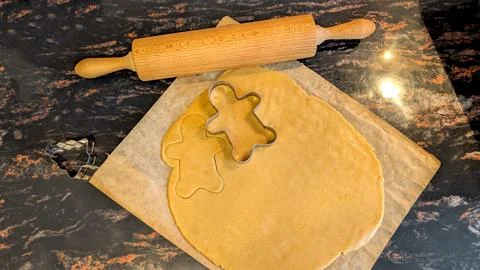 Rolling Raw Gingerbread Dough with Cookie Cutters on Kitchen Counter Foto stock