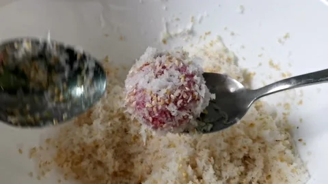 Rolling Red Glutinous Balls on a Grated Coconut and Sugar Stock Footage 149407922