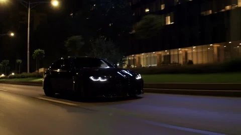 Rolling shot of BMW black car driving fast on a wet city road at night 库存影片 341957073