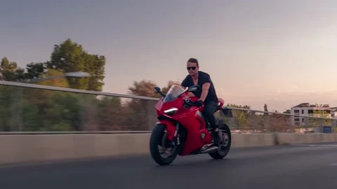Rolling shot of man biker riding red Ducati Panigale motorcycle on the street Stock Footage 214080775