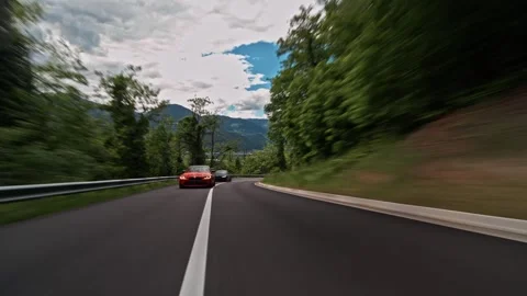 Rolling shot of a matte black bmw m4 leading a red m4 on a winding mountain road Stock Footage 328647660