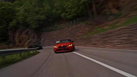Rolling shot of orange BMW M3 sports car drifting around mountain hairpin curve Stock-Footage 328647742