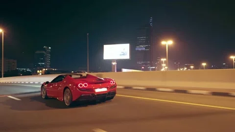 Rolling shot of Red Ferrari F8 Tributo supercar driving at night in Dubai Stock Footage 200032032