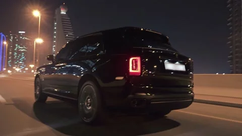 Rolling shot of Rolls Roys Cullinan car driving on the street at night in Dubai Video stock 200033512