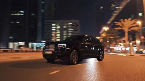 Rolling shot of Rolls Roys Cullinan car driving on the street at night in Dubai Video stock 200033598