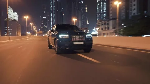 Rolling shot of Rolls Roys Cullinan car driving on the street at night in Dubai Video stock 200033826