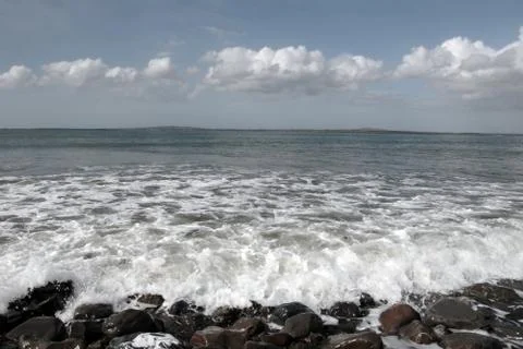 Rolling waves crash on pebbles Stock Photos