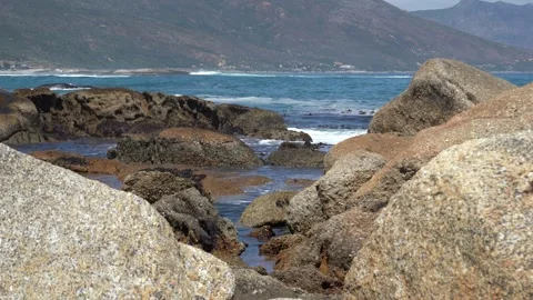 Rolling waves crashing over big granite beach boulders Stock Footage 331695609