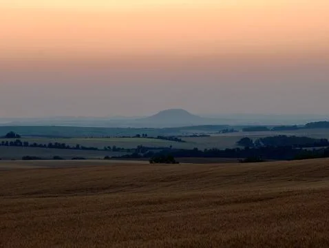 Rolling wheat field in foreground with distant flat topped hill beneath pas.. Stock Photos