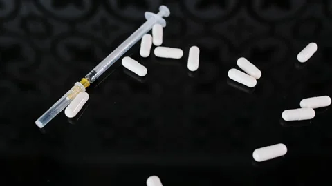 Rolling White medecine Capsules to thin syringe that lies on black glass Stock-Footage 261970210