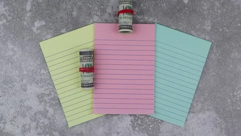 Rolls of 100 dollar banknotes on colored notepads. Stop motion, top view Vídeo Stock 149198241