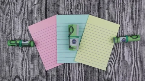 Rolls of 100 Euro banknotes on colored notepads. Stop motion, top view Vídeo Stock 148941779