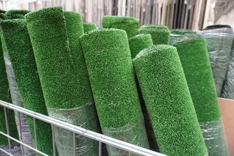 Rolls of artificial grass in the store, green carpet, close-up. Stock Photos