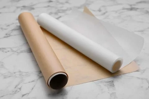 Rolls of baking paper on white marble table Stock Photos