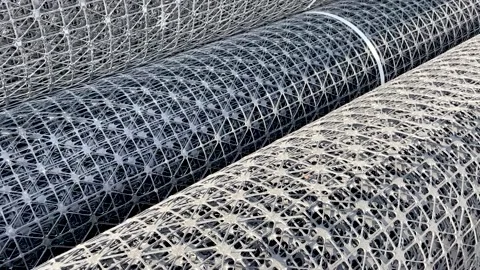 Rolls of black plastic geogrid prepared for reinforcement the roadbed Stock Footage 236208566