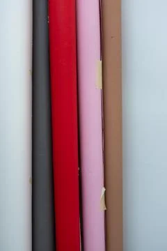 Rolls of colored paper stand against a wall in a workspace where creative p.. Stock Photos