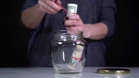 Rolls of dollars are put in a glass jar and closed with a metal lid Video stock 127546019