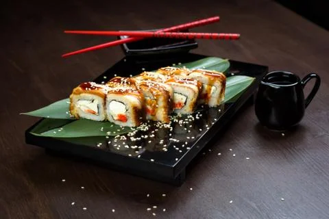 Rolls with eel and cheese on the board with sauce and red chopsticks Foto stock