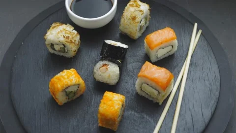 Rolls mini set on a round board next to sticks, soy sauce and baked champignons Stock Footage 169180546