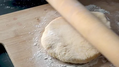Rolls out the dough for baking bread with a rolling pin on a wooden board close Stock Footage 246708463