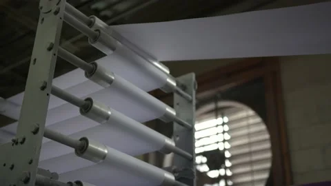 Rolls of Paper enter Printing Press in Spools at Factory to make paper products Stock Footage 136491478