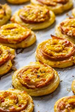 Rolls of puff pastry with ham bacon cheese sesame on baking tray Stock Photos