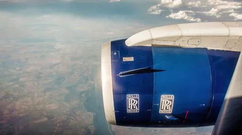 Rolls Royce logo on an airplane engine, flying above clouds Stock Photos